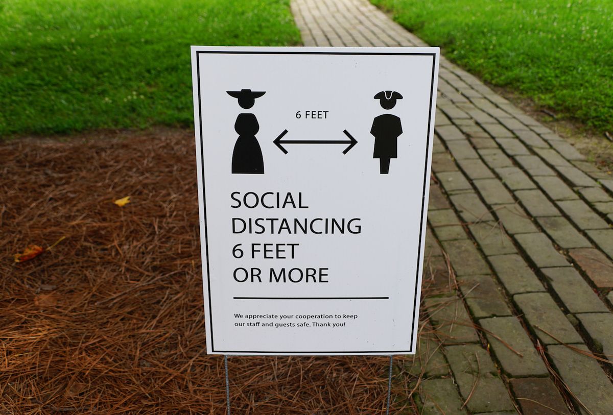 A lawn sign asking visitors to Williamsburg, Virginia to stay 6 feet apart during a tour.