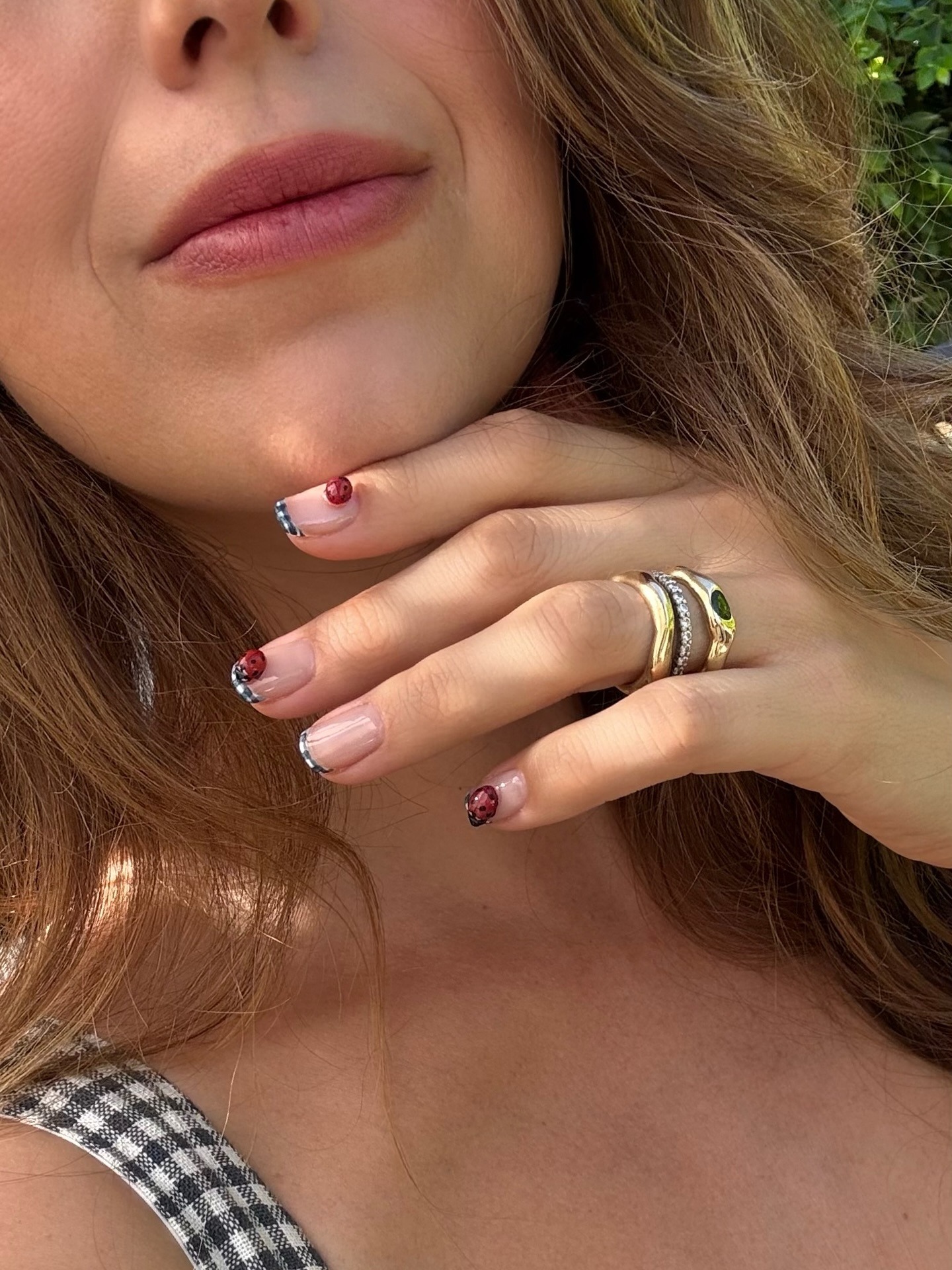 A woman taking a selfie with gingham French tip nails and a matching dress