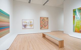 Interior view of a gallery space at The San Francisco Museum of Modern Art (SFMoMA) featuring white walls, wood flooring, a bench and colourful art on the walls