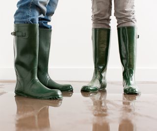 shot of people wearing green wellies stood on floor with signs of water