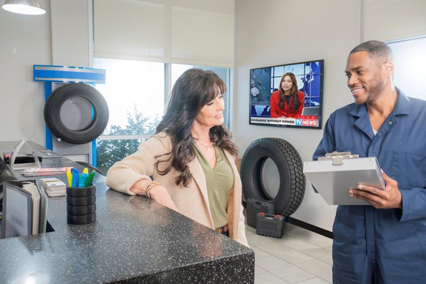 Man and woman in an auto repair shop with a TV showing streaming video channels 