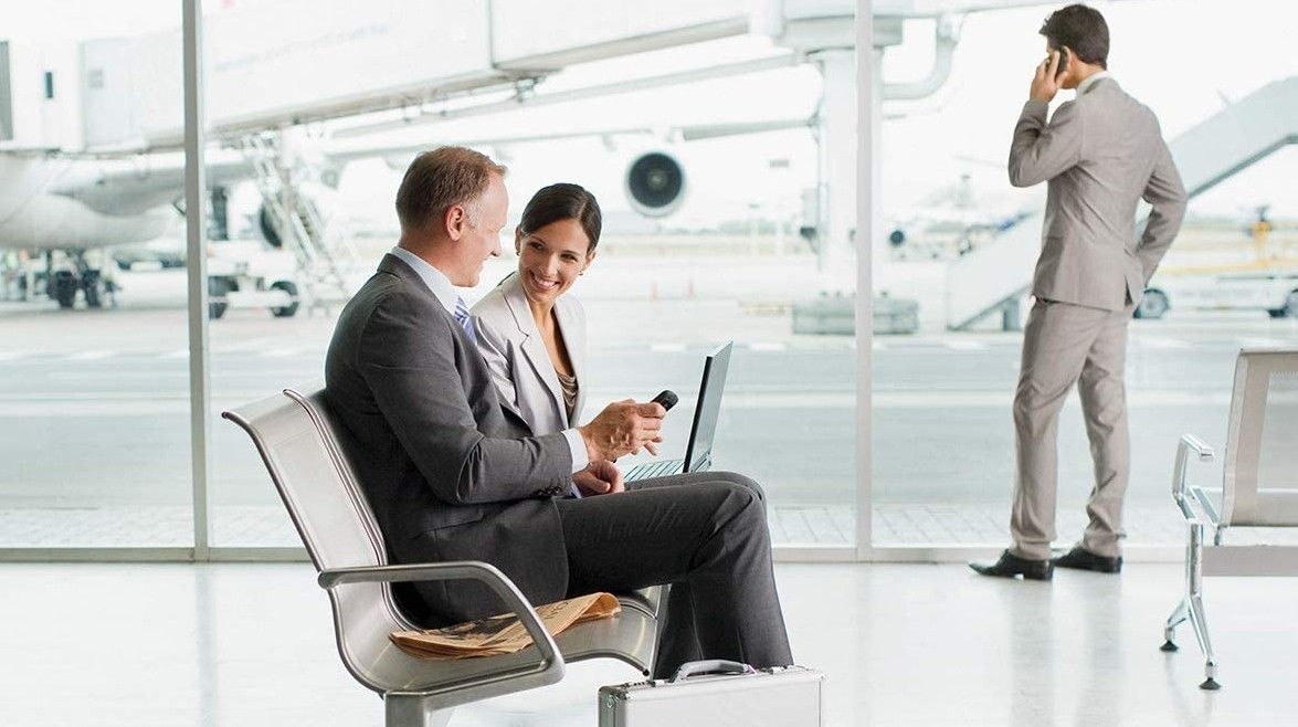 best mobile hotspot: Man and woman using Netgear mobile hotspot to connect laptop in airport waiting area