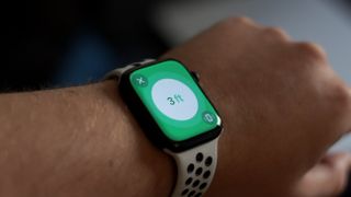 An Apple Watch Series 9 on a wrist with a green screen displayed, showing distance in feet