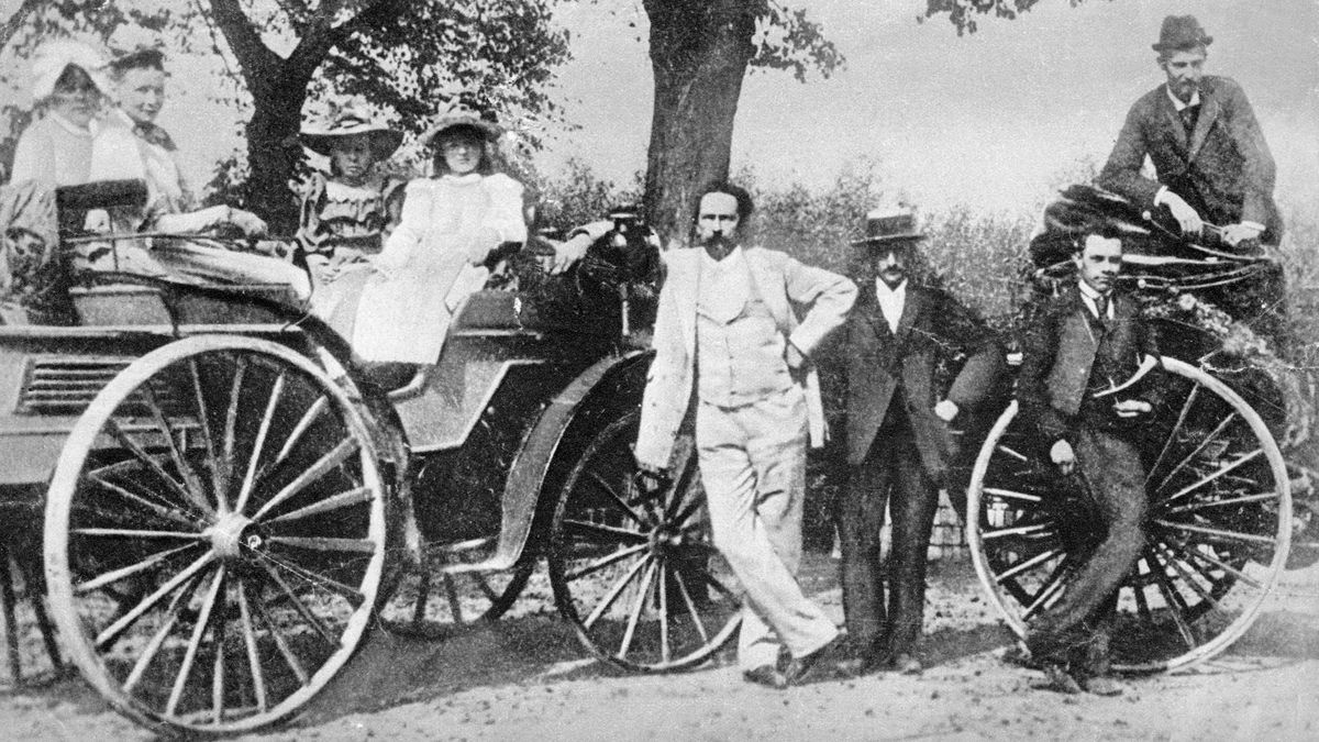 a black and white photo of a group of people with an old-fashioned car