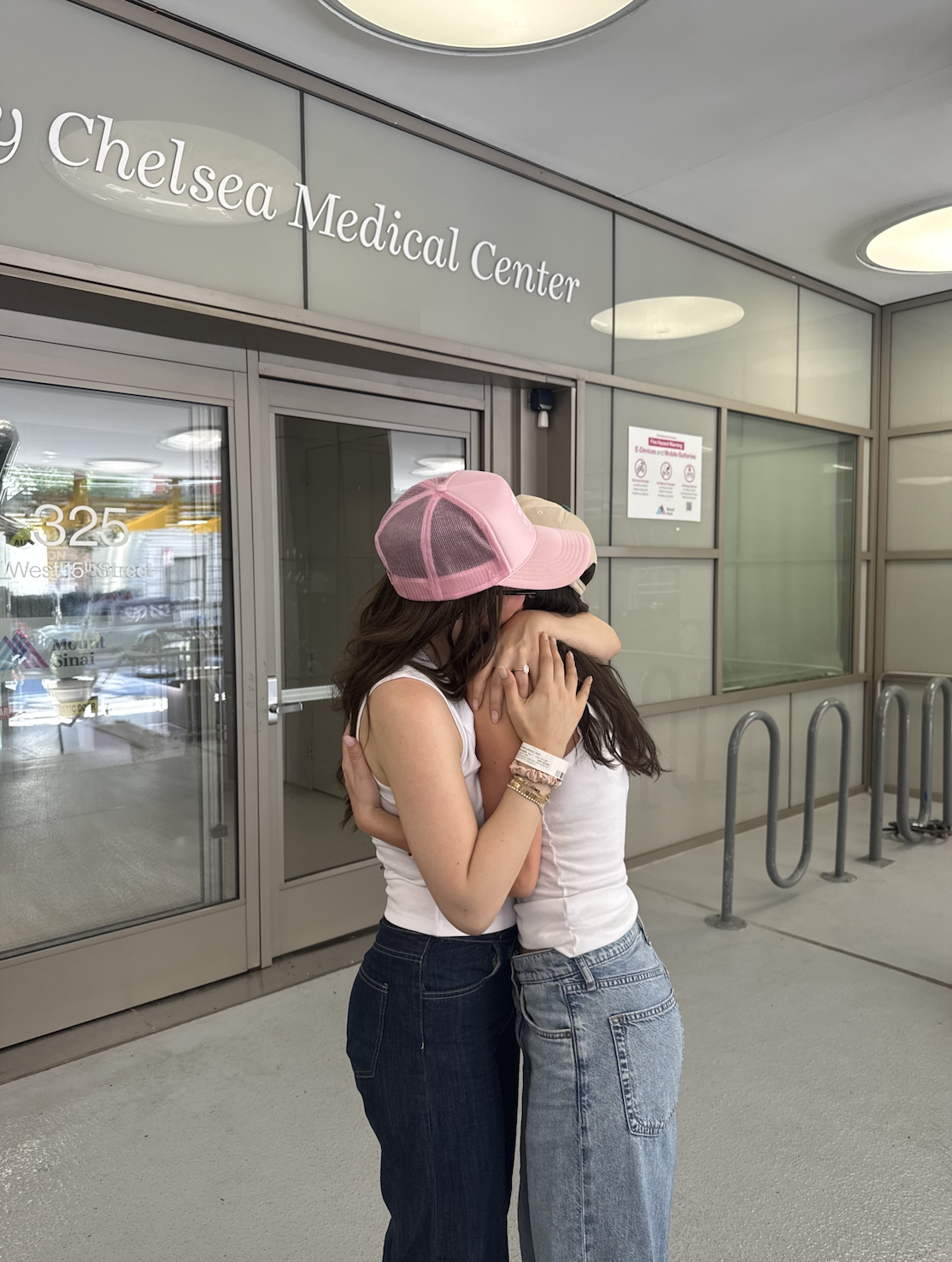 two women wearing jeans, hugging