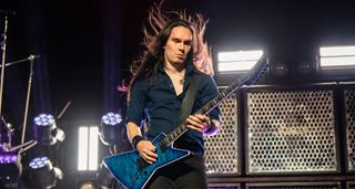 Teemu M&auml;nysaari performs live with Megadeth, in front of some guitar cabinets with industrial metal grilles.