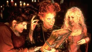 Kathy Najimy, Bette Midler, and Sarah Jessica Parker stare at their magic book in Hocus Pocus.