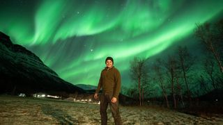 A photo of Josh Dury standing infront of a spectacular aurora in Tromso, Norway