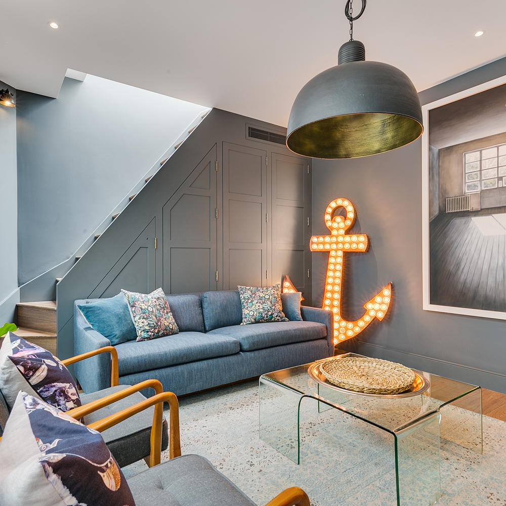 tv room with grey wall blue sofa with cushion glass table