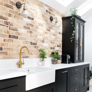 exposed brick wall, kitchen sink and black cabinets