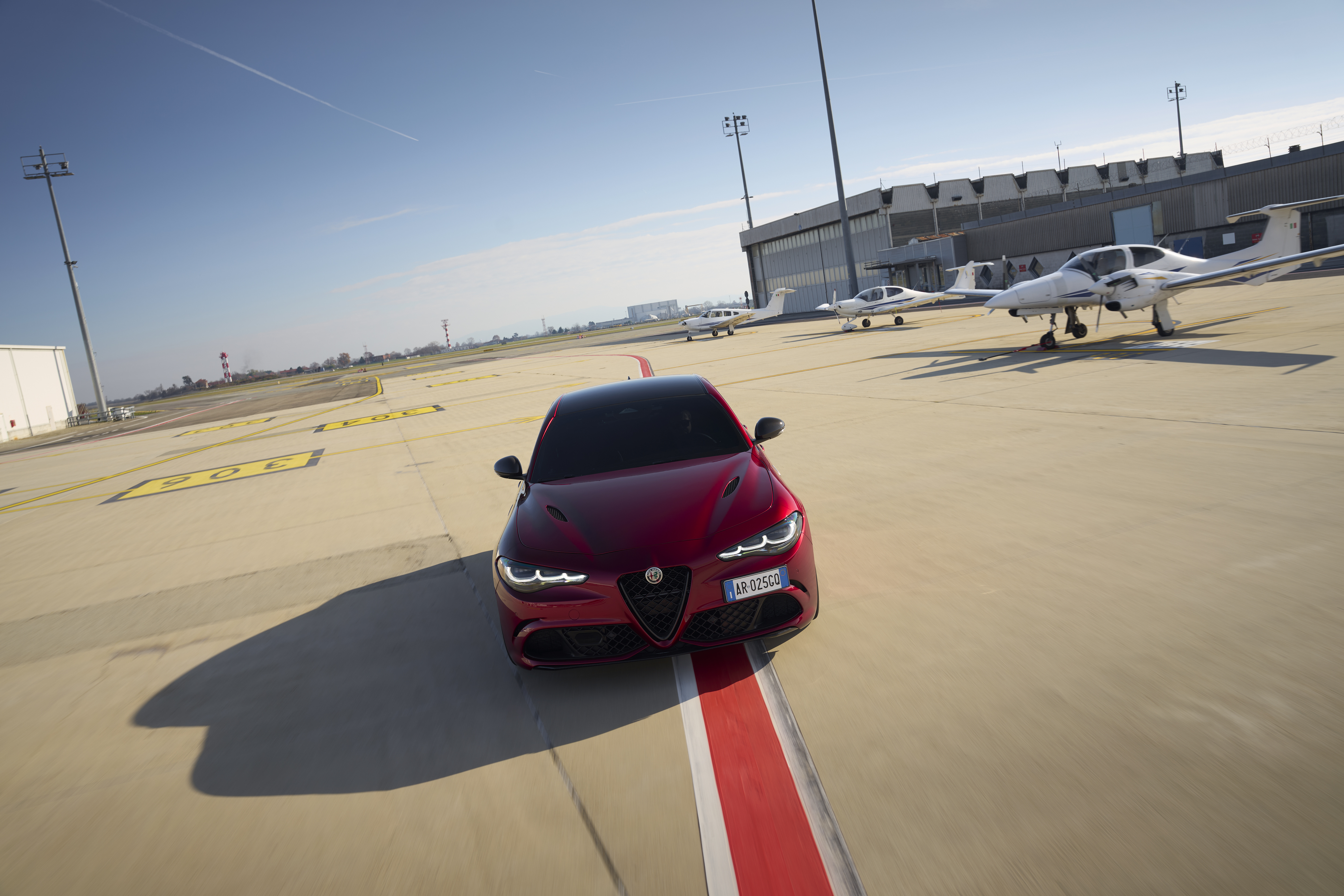 A red Alfa Romeo Giulia zooming about on an airfield