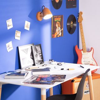 orange wall light above white desk with blue painted wall behind