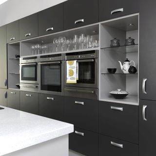 Kitchen with dark grey cabinetry and built in appliances