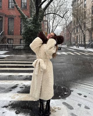 Kit Keenan poses in an oversize coat and mittens while visiting the West Village.