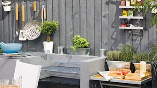 Outdoor kitchen area with built-in bbq and utensils hanging behind a work surface