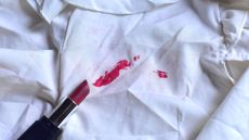 An open red lipstick on a white shirt