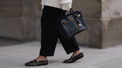 A woman wearing expensive shoes and a Birkin bag