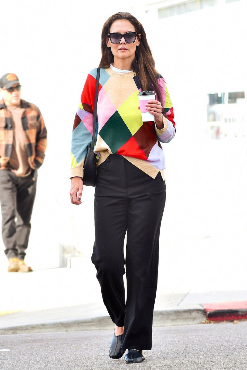 Katie Holmes wearing harlequin Boden jumper, shades and flat shoes, carrying a coffee