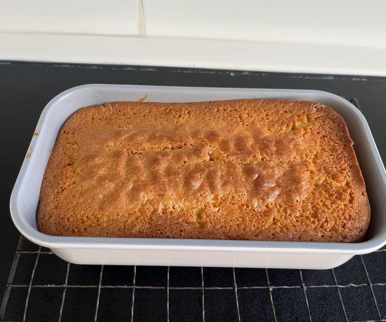 A grey loaf tin with a golden cake inside viewed from above