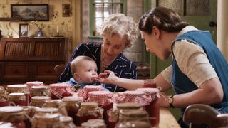 Patricia Hodge as Mrs Pumphrey holds baby Jimmy as Anna Madeley as Mrs Hall feeds him jam in All Creatures Great and Small.