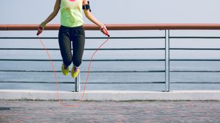 legs of woman skipping outside by water