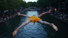A man dives into the Canal Saint-Martin as temperatures rise during a heatwave in Paris, France