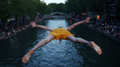 A man dives into the Canal Saint-Martin as temperatures rise during a heatwave in Paris, France