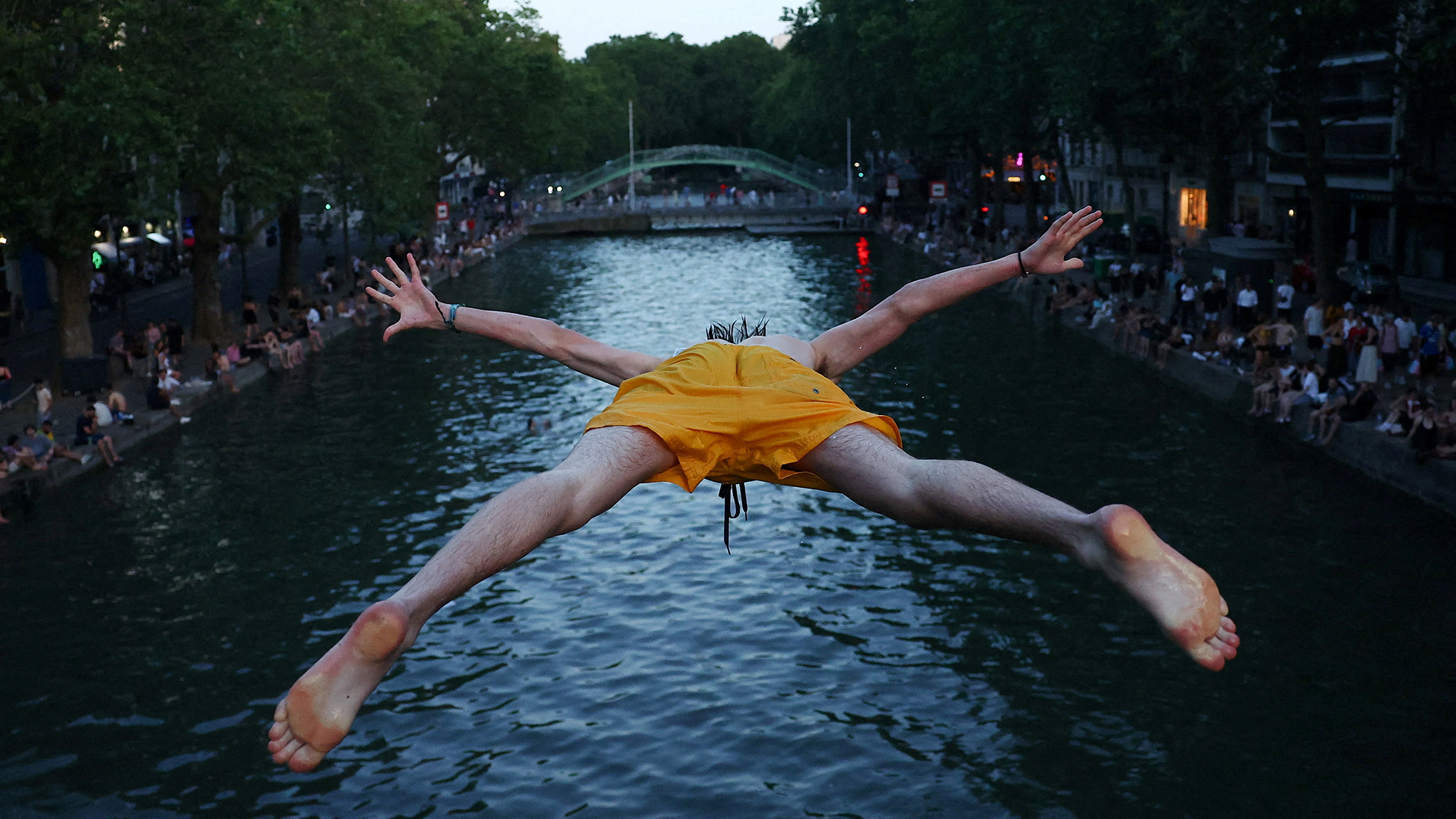 A man dives into the Canal Saint-Martin as temperatures rise during a heatwave in Paris, France