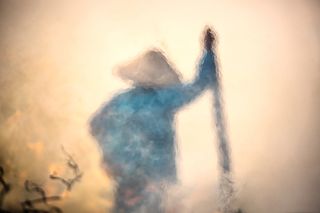 a blurry image of a farmer leaning on a stick