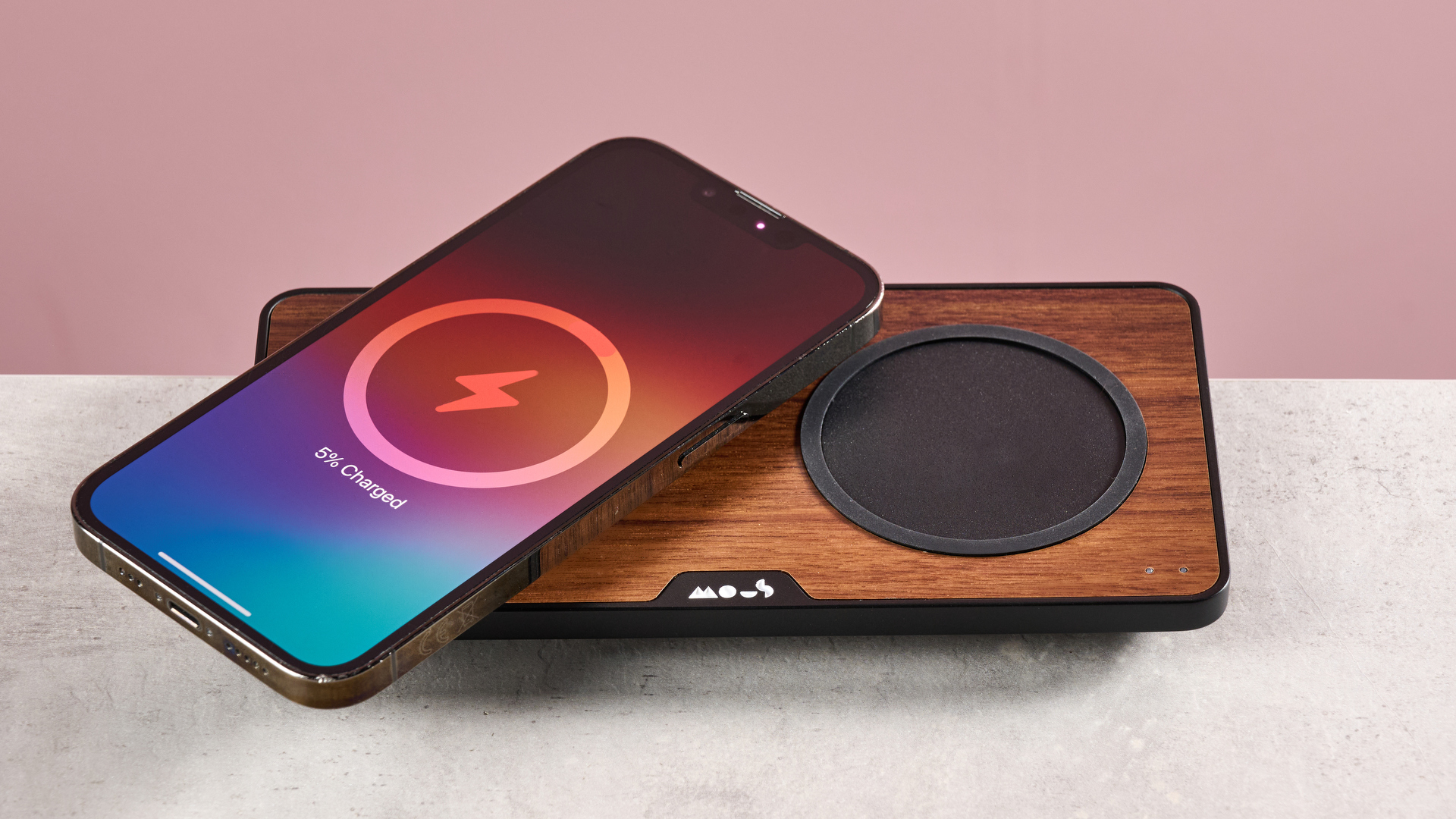 An iPhone sits at an angle on the Qi2 pad of the Mous Charging Station.