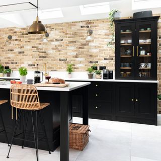 exposed brick wall with black kitchen cabinets behind island unit