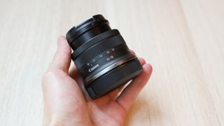 A Canon RF-S 10-18mm f/4.5-6.3 IS STM lens held in a hand