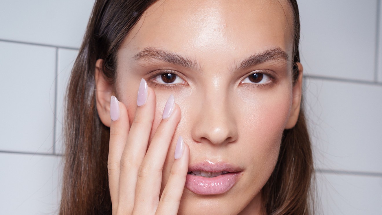 woman with oval nails putting her hand on her face
