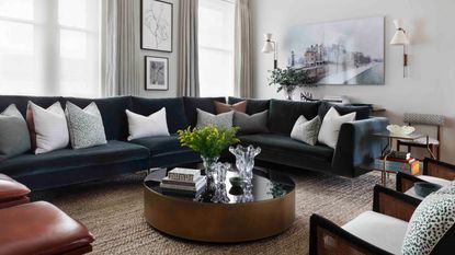 neutral living room with dark gray sectional, jute carpet and round coffee table