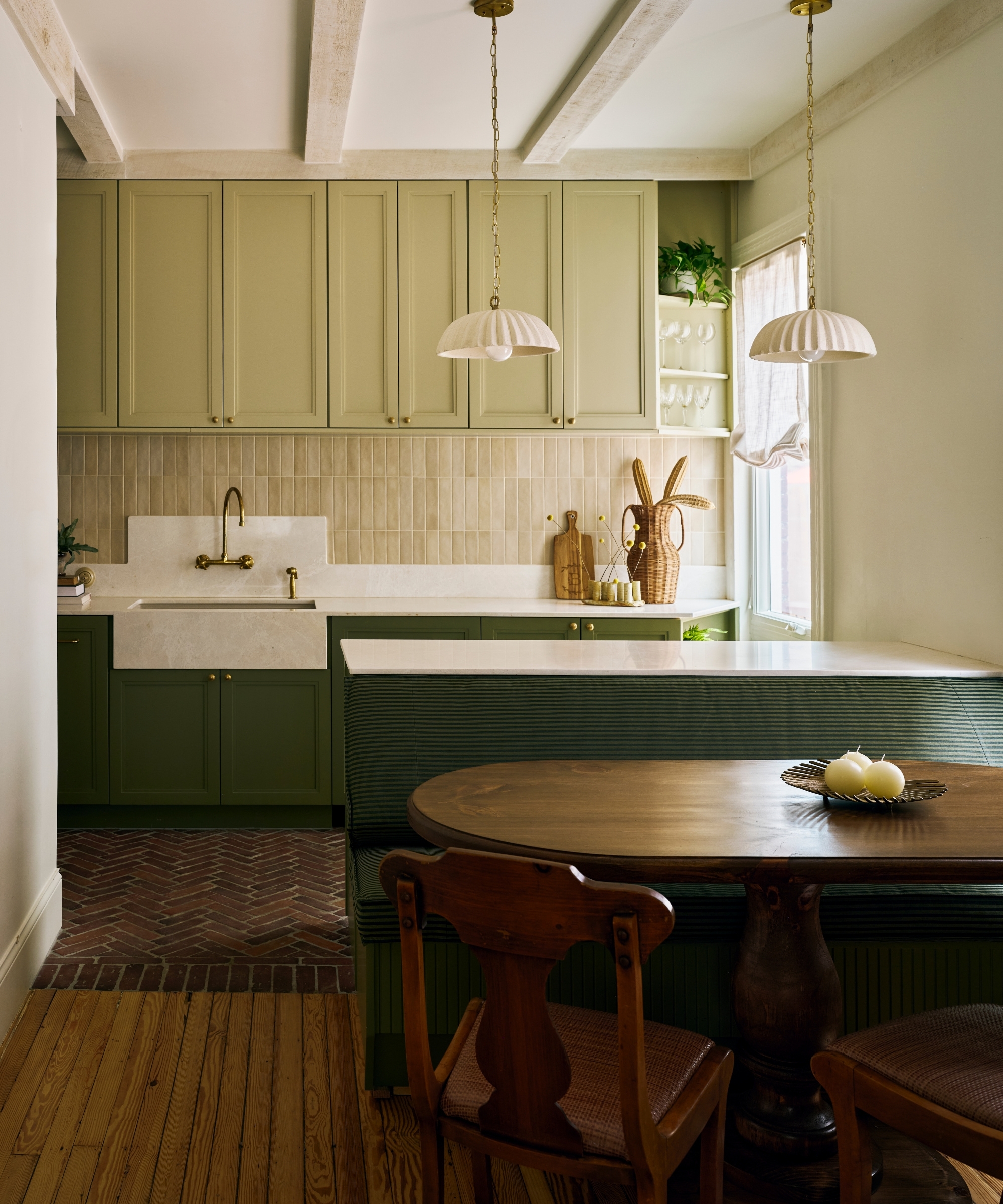 A small kitchen with dark green perimeter cabinets and island, and pale apple green wall cabinets