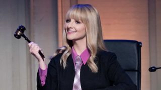 Abby wearing a tie under judge's robe, holding gavel in Night Court musical episode