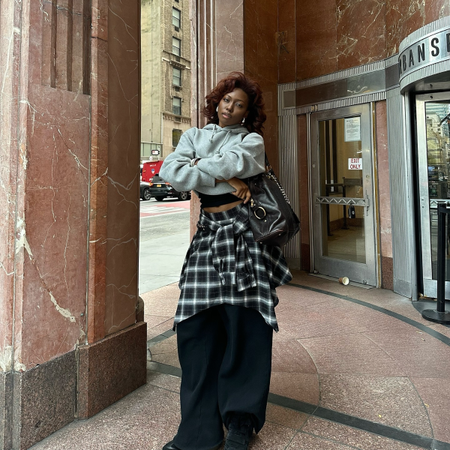 Influencer Chanel McKinsie wearing a plaid shirt with black trousers and grey hoodie. 
