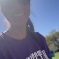 Meghan Markle wearing a purple Northwestern sweatshirt and sunglasses outside with trees behind her