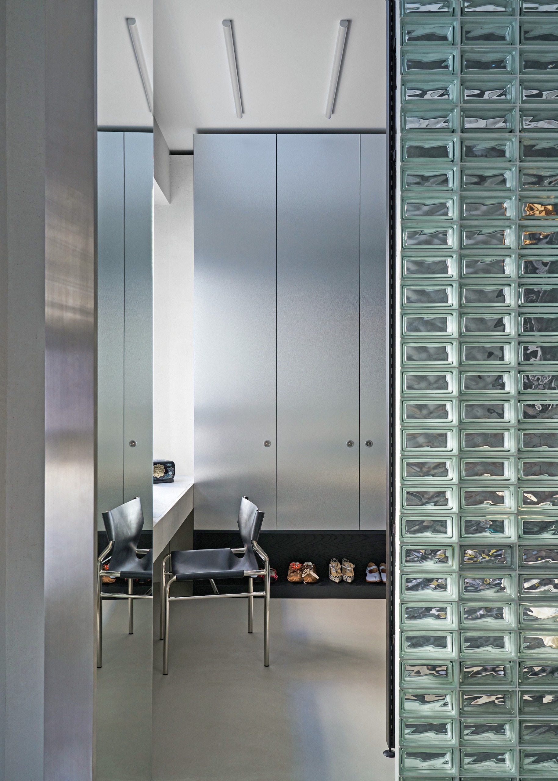 Glass block screen leading to wardrobe area with chrome cabinetry and chrome chair