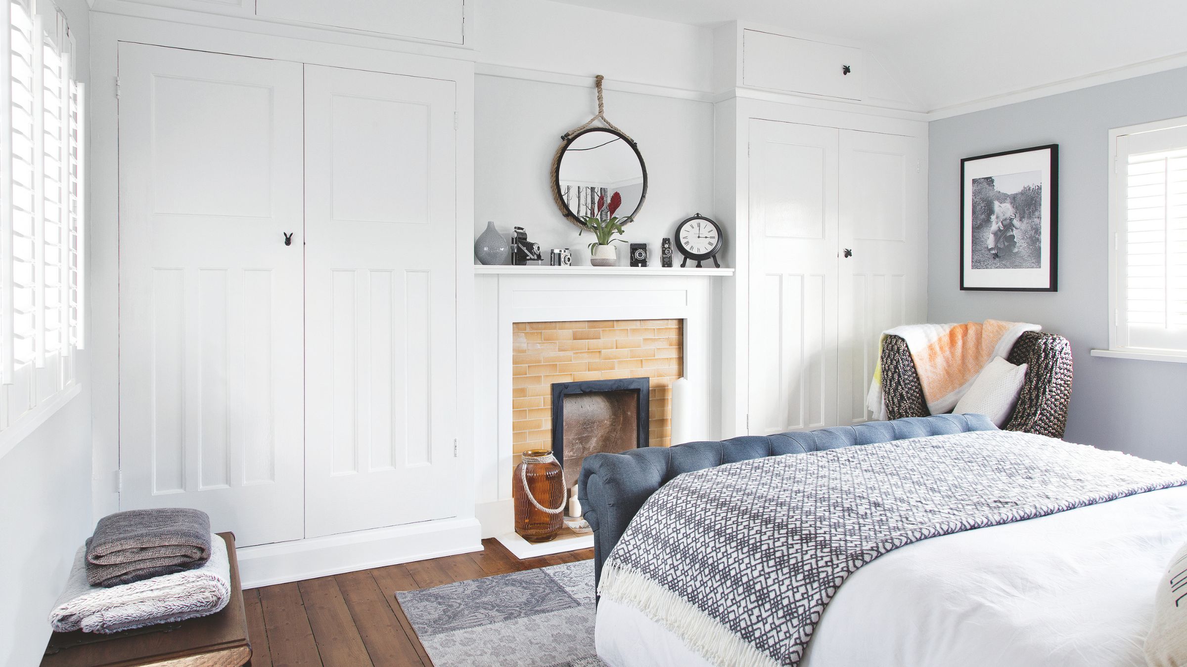 White painted bedroom with white fitted wardrobes either side of a fireplace
