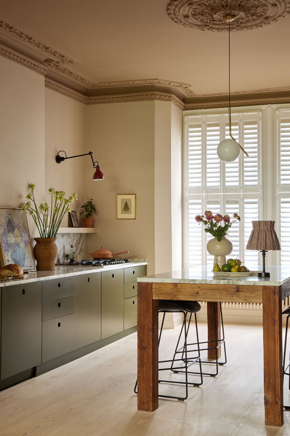A neutral kitchen with warm white walls, green cabinets, and a wooden island