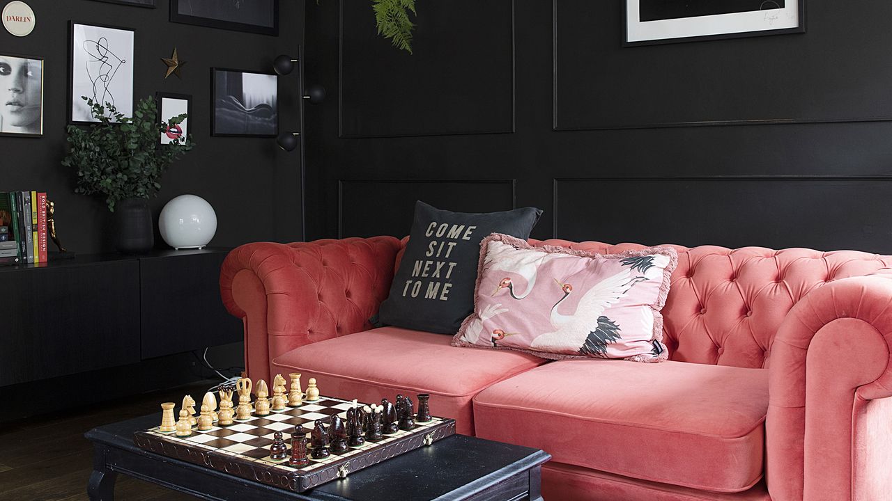 Black living room with pink velvet sofa.