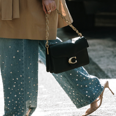 woman carrying a Coach tote and a pair of jeans and heels in New York City 