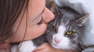 Woman kissing grumpy-looking cat