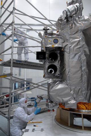technicians assemble a satellite in a clean room