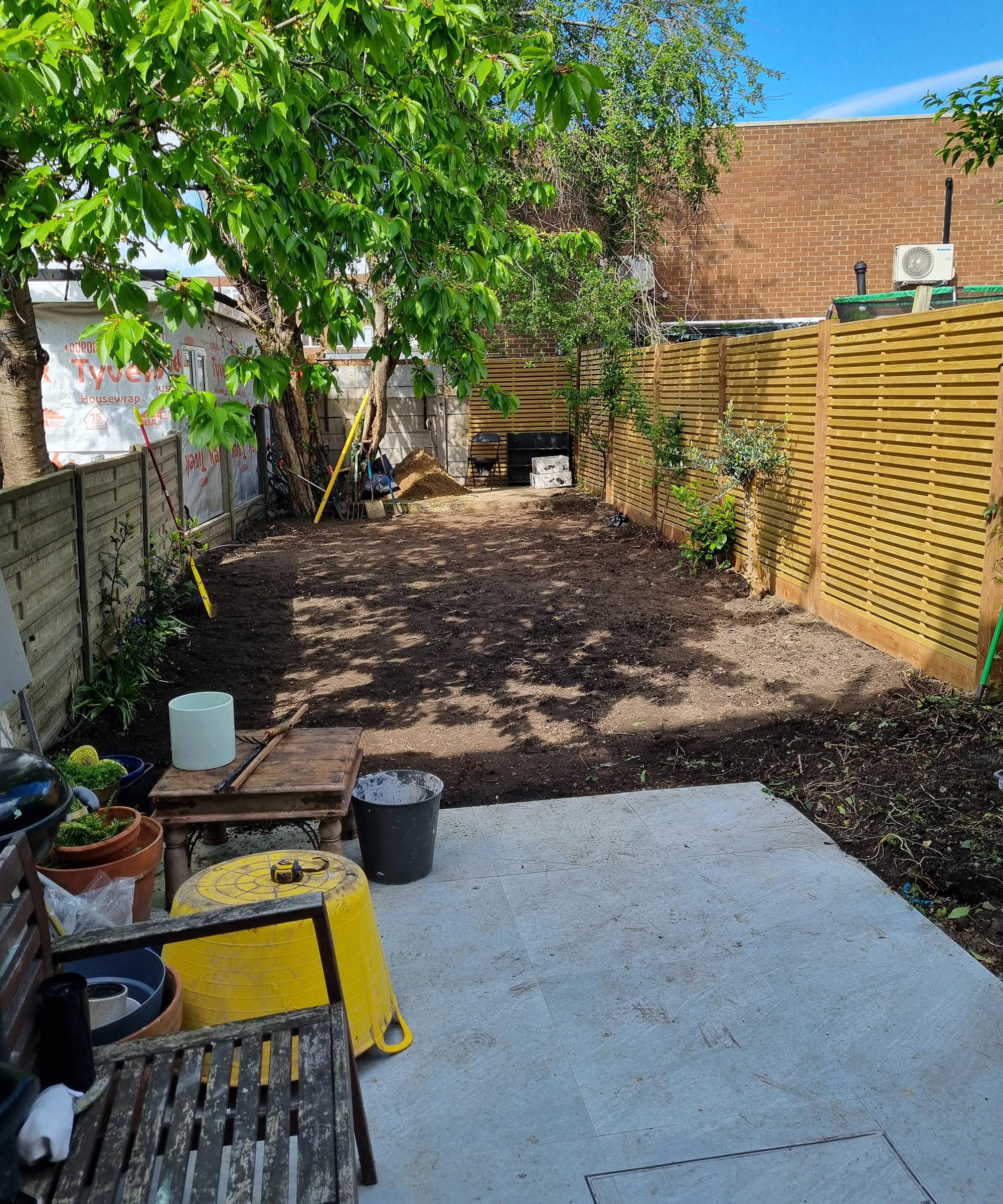A porcelain patio paving in front of a garden which has been dug over and levelled