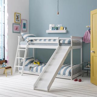 A white low midsleeper bunk bed in a blue childrens bedroom with blue and white striped bedding