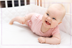 baby girl smiling in cot