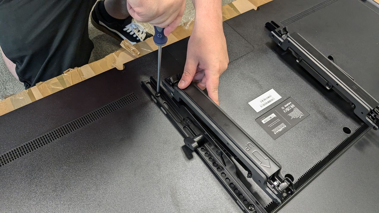 Sanus OLT7 brackets with person using screwdriver