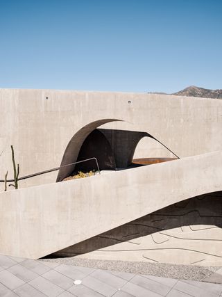 hill house montecito, flowing concrete house in the californian context with arid landscape and a tree around